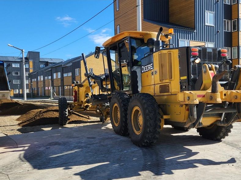Motoniveladora trabajando junto a edificios en construcción